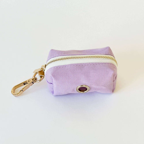 Een kleine paarse tas met gouden rits en sleutelhanger, perfect voor poepzakjes en snacks.