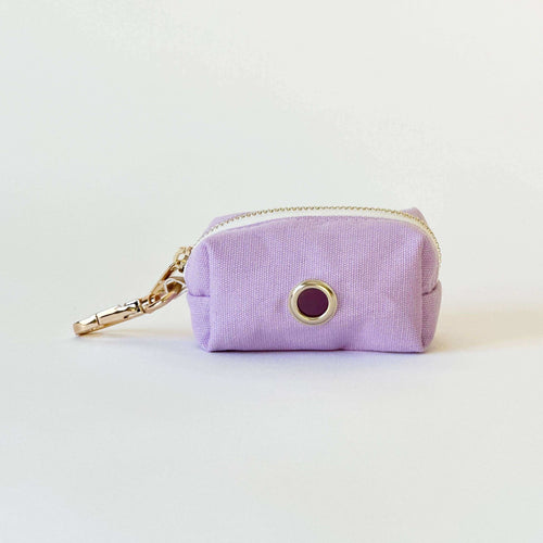 Een kleine paarse tas met gouden details, perfect voor poepzakjes en snacks onderweg.